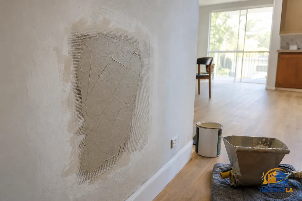 Medium drywall repair with mesh patch and first mud coat in a Van Nuys apartment, texture blending tools nearby