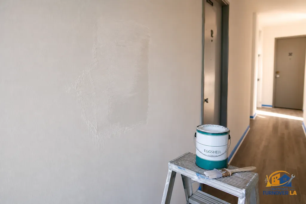 Hallway drywall patch and trim prep in a Koreatown apartment repaint, with taped baseboards and eggshell paint ready