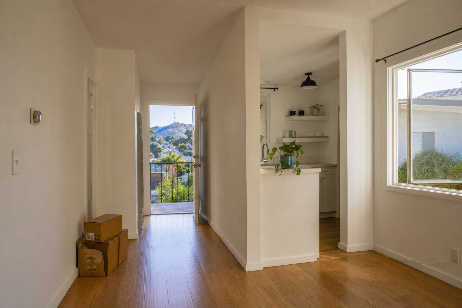 Freshly turned mid-century LA apartment with clean white walls, hardwood floors, and open windows showing hills