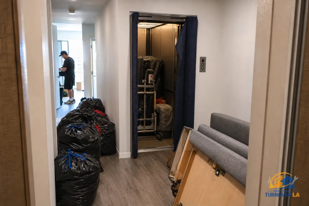 West Hollywood hallway staging junk bags and a disassembled sofa for elevator load-out during an apartment cleanout