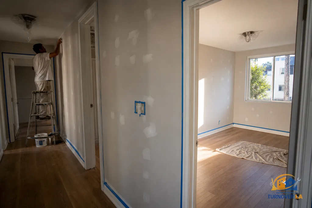 LA hallway and bedroom during repaint prep with taped trim and drying patches, showing scope factors that affect interior painting cost
