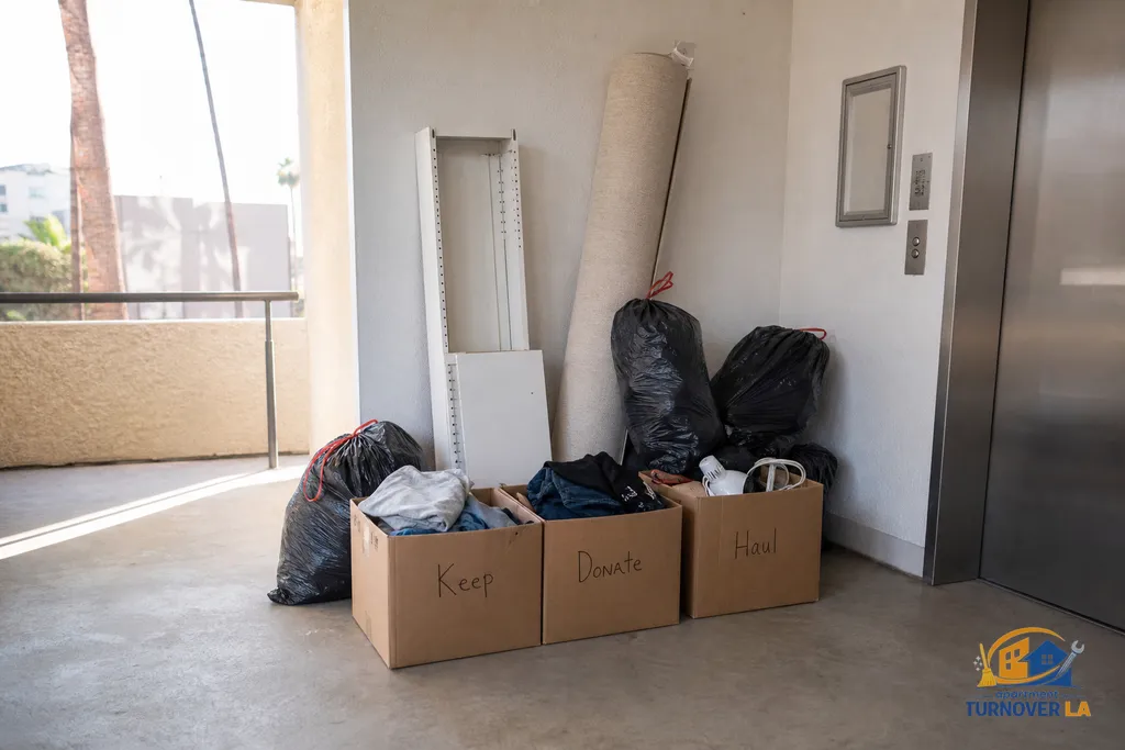 Labeled piles for Keep, Donate, Haul in a Los Angeles studio entryway beside an elevator during a junk removal